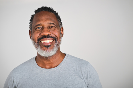 front view portrait of a confident middle aged Dominican man with a grey t-shirt in a white studio background