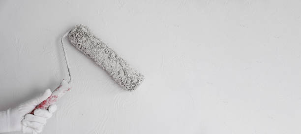 istock Painting a bare wall with a roller with white paint. Apartment painting 2135648508
