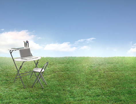Outdoor office desk and chair in a backyard with green grass lawn