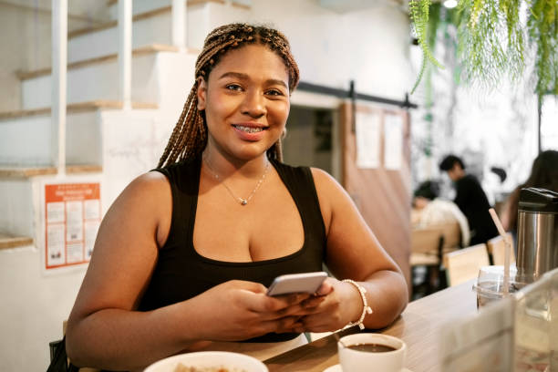 istock Beautiful african woman using her mobile phone while sitting at cafe 2135650261