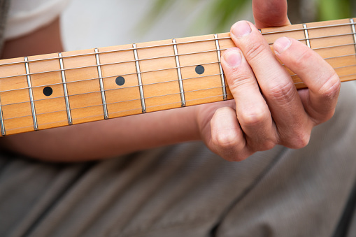 Close up of the hand of a musician playing a chord in his guitar.