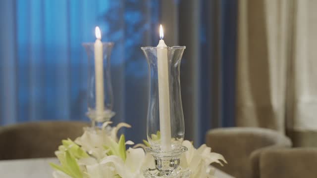 White Lit Candles In Tall Glass Candelabra On Dining Table. Elegant Table Setting. closeup shot