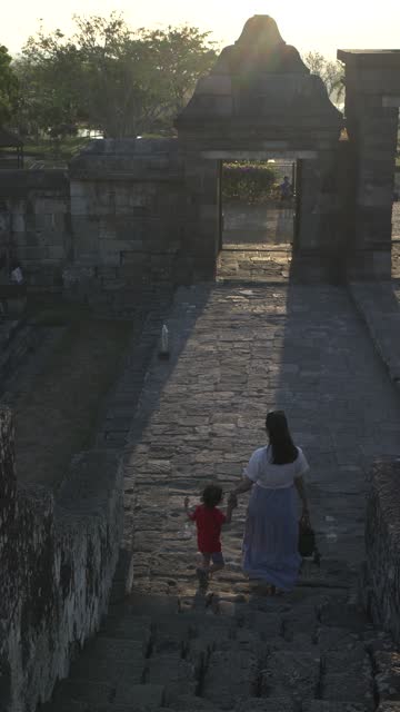 Chinese mother holding her son hand when moving down stair on  Ratu Boko Temple, Yogyakarta