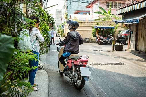 Woman greeting a senior female motorbike driver for a ride in front of her house in the city