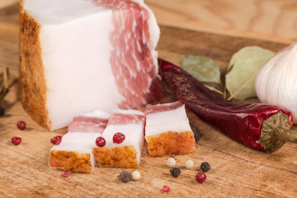 istock Partly sliced salted pork fatback among spices on cutting board 2135686352