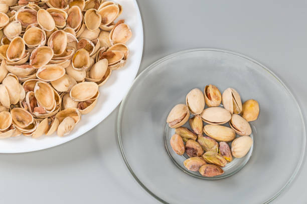 istock Partly peeling pistachio nuts on saucer and empty shells 2135691191