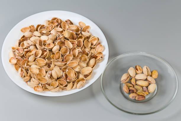 istock Partly peeling pistachio nuts on saucer against the empty shells 2135691762