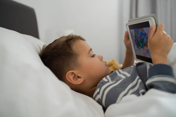 istock Toddler Boy Engrossed in Tablet Technology in Bed 2135706182