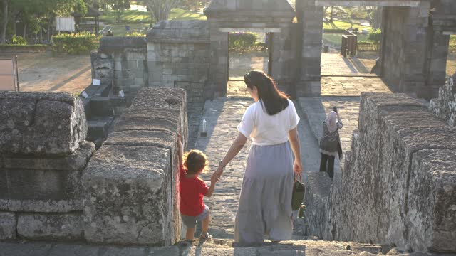 Chinese mother holding her son hand when moving down stair on  Ratu Boko Temple, Yogyakarta