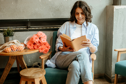 Woman is sitting in a cafe and relaxing with a book
