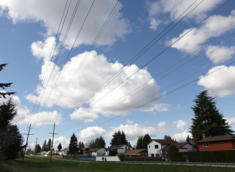 Spring clouds drift over rows of power lines along an easement. Houses built in the 1980s line the Green Timbers Greenway in the Fleetwood-Tynehead neighbourhood of Surrey, British Columbia.