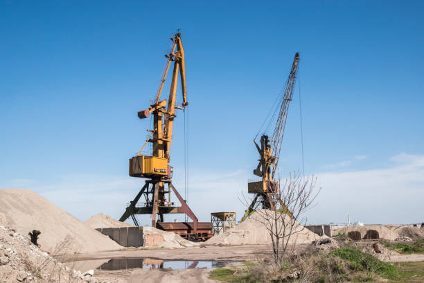 Port industrial cranes at river sand unloading depot on clear sunny day