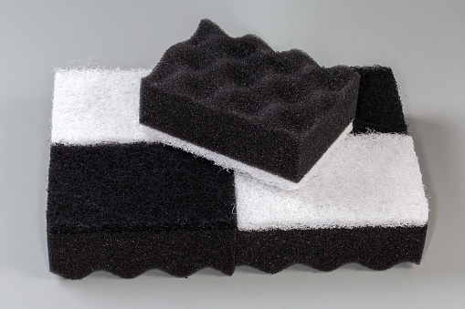Several black and white kitchen soft synthetic cleaning sponges with hard urethane abrasive layer on a gray background