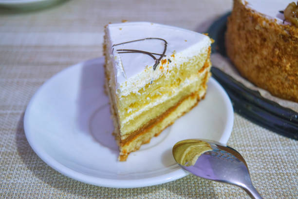 A piece of sponge cake with cream on a plate on a table background close-up.