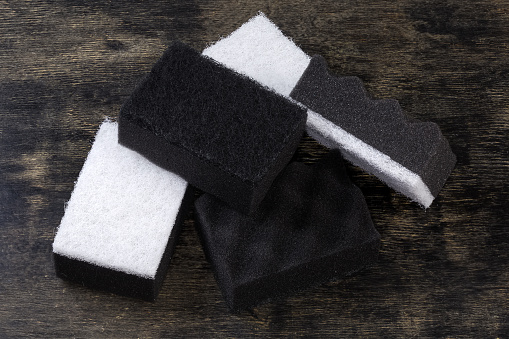 Several black and white kitchen soft synthetic cleaning sponges with hard urethane abrasive layer on a black surface