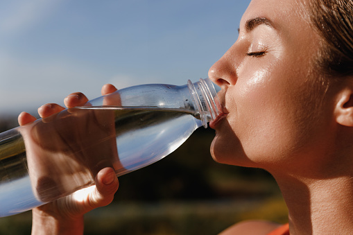 Young woman takes a refreshing drink of water after a workout session.