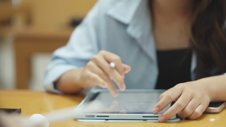 A woman is writing on a tablet with a pen