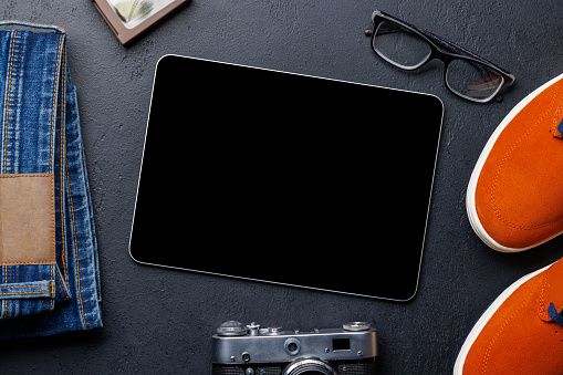 Men's Clothing on stone Background: Jeans, Sneakers, Eyeglasses, Flat Lay with blank screen Tablet with Copy Space