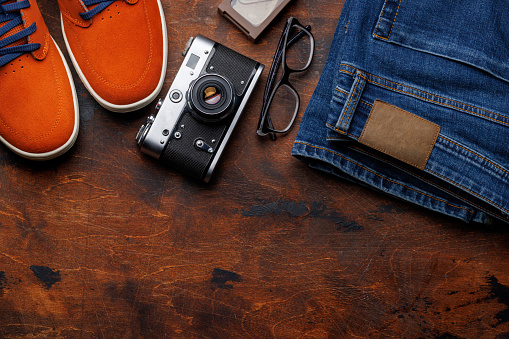 Men's Clothing on wooden Background: Jeans, Sneakers, Eyeglasses, Flat Lay with Copy Space