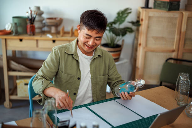 istock Casually clothed artist working on his glass bottle design at small workshop 2135780146