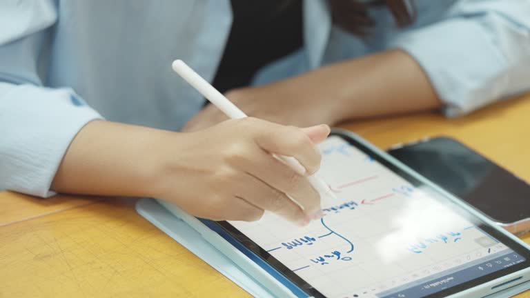 A woman is writing on a tablet with a pen