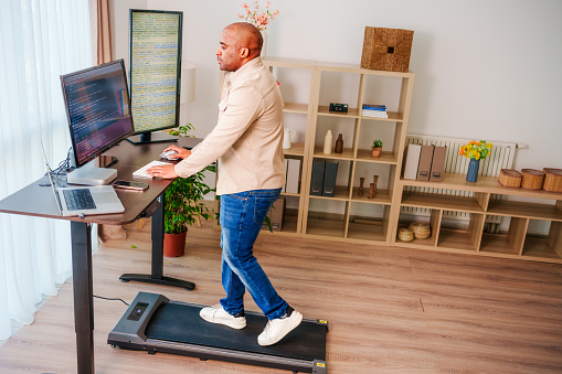 Black Man is  Working at Home Office and  Walking on Under Desk Treadmill