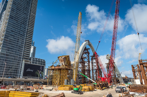 Miami, USA - April 3, 2024: View of heavy metal structures and machinery supporting decorative arches that are part of the new viaduct being built near downtown Miami (Project I-395/SR 836/I- 95), where new luxury housing complexes are being developed.