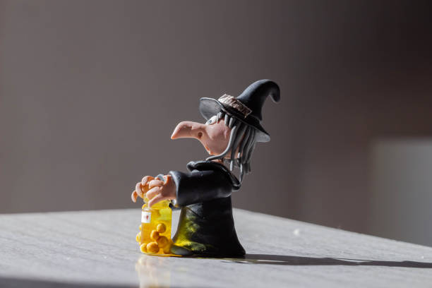 Halloween witch figurine with candles and magic potion in glass bottle stock photo