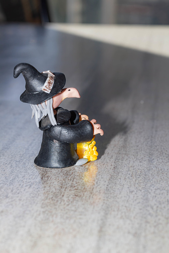 Witch figurine with bottle of potion and candle on the table.Candle holder with the figure of a witch on a mirror background