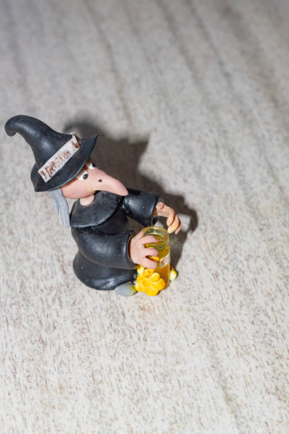 Halloween witch figurine with bottle of beer on wooden background. stock photo