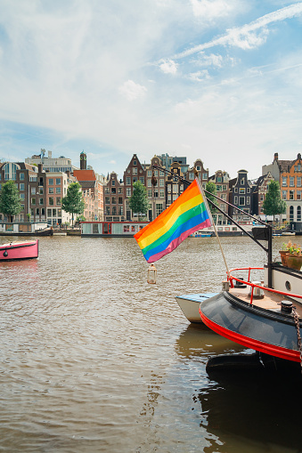 LGBTQ+ flag on the boat on canal in Amsterdam, Netherlands in summer