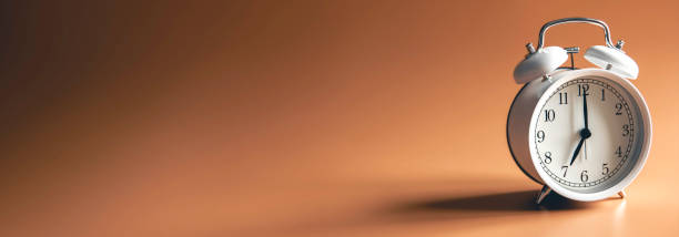istock White alarm clock on brown background isolated. 2135837527