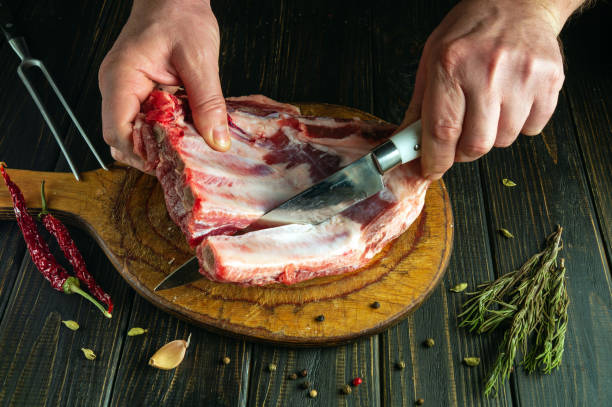 istock The chef uses a knife to cut the meat from the bone on a kitchen board before preparing the dish. The process of cooking meat on the kitchen table by the hands of a butcher 2135839652