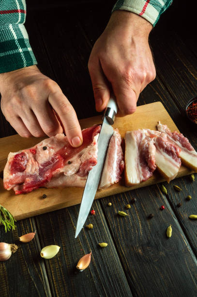 istock The cook hands use a knife to cut lard or pork belly on a kitchen board before preparing it for dinner. The concept of preparing a hearty and fatty food 2135840369