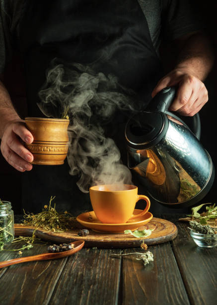 istock Making healthy green tea from dry medicinal herbs. Adding boiling water to a mug with herbs. Traditional medicine concept. Treating the flu virus at home 2135840727