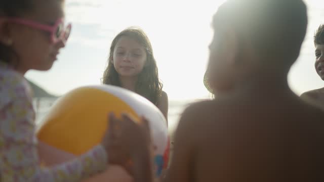Friends children playing with beach ball on the beach