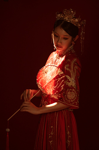 Stunning backlit portrait of an Asian Chinese woman in traditional bridal tea dress holding a hand fan