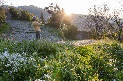 Mature man takes photo in lush field at sunset