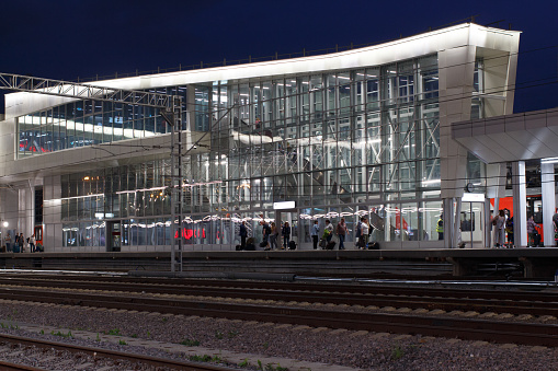 Peron with passengers and overpass at night at the station. Moscow, Russia, June 09, 2022.