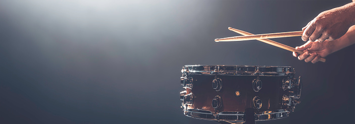 A man plays a snare drum on a dark background, copy space. Web, social media banner template.