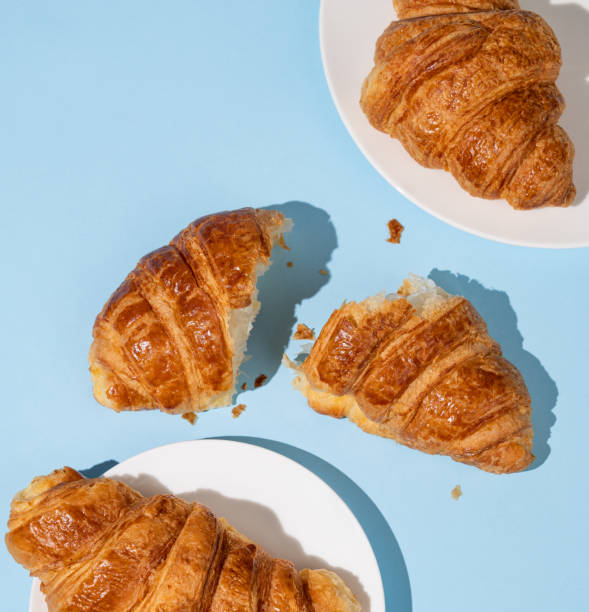 istock Flat lay of  fresh croissants on blue background with shadow. Creative layout and concept of healthy food and french breakfast. 2135911470