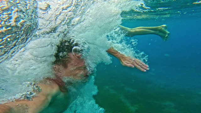 SLO MO POV Shot of Carefree Shirtless Man Diving in Sea From Yacht during Summer Vacation