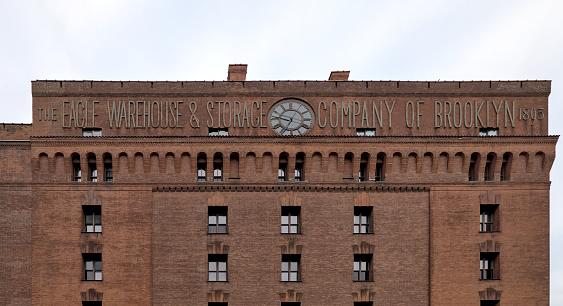 Brooklyn, NY - Apr 1, 2024: The Eagle Warehouse Storage Company of Brooklyn 1893 sign on top of a historic clocktower red brick building in downtown New York City.