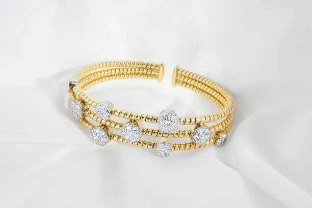 Luxurious gold bracelet with diamond accents presented on satin fabric