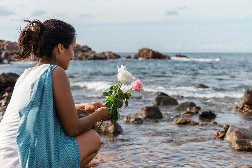 brazilian woman throwing flowers into the sea paying homage to Yemanja,
