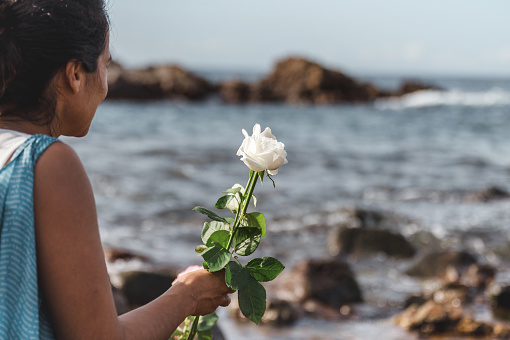 brazilian woman throwing flowers into the sea paying homage to Yemanja,