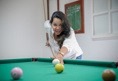 Beautiful woman spends her free time playing billiards pool.
