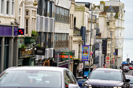 West Street Brighton BN1, Brighton And Hove, East Sussex, Southeastern England, United Kingdom, Britain, Europe - 16th March 2024: City Life, Cityscape - Amidst the traffic on West Street, and an urban, street view of Brighton and Hove City, a coastal city in East Sussex, England, UK, people strolled along the street while also cars and local double-decker buses navigated the lively flow, capturing the essence of this urban scene on West Street in Great Britain in Europe.