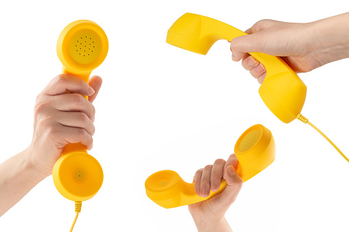 Yellow handset in woman hand isolated on white. Copy space.