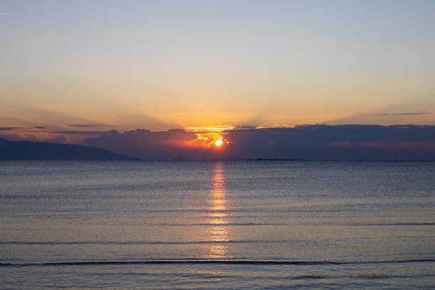 The dawn sun casts a radiant path across the quiet sea